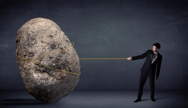Businessman pulling huge rock with a rope — Stock Photo, Image