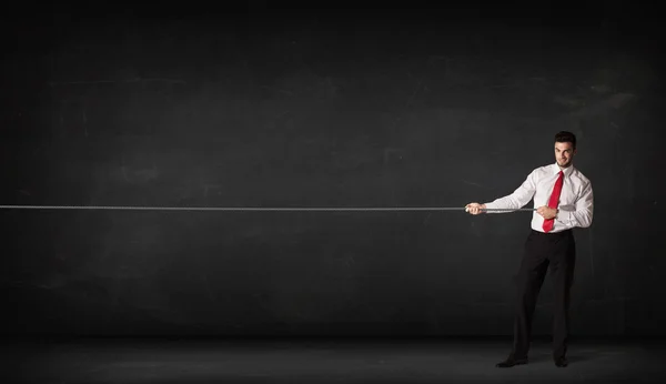 Businessman pulling rope on grey background — Stock Photo, Image