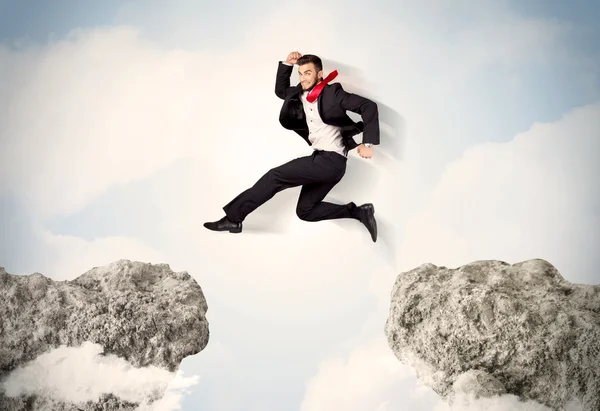 Glad affärsman hoppar över en klippa — Stockfoto