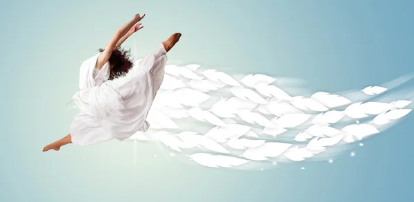 Healthy young woman jumping with feathers around her — Stock Photo, Image