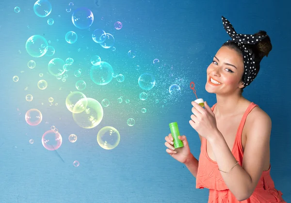 Senhora bonita soprando bolhas coloridas no fundo azul — Fotografia de Stock