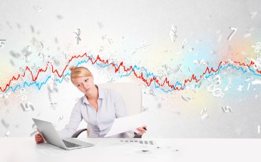 Borsa grafiğiyle masada oturan iş kadını. 