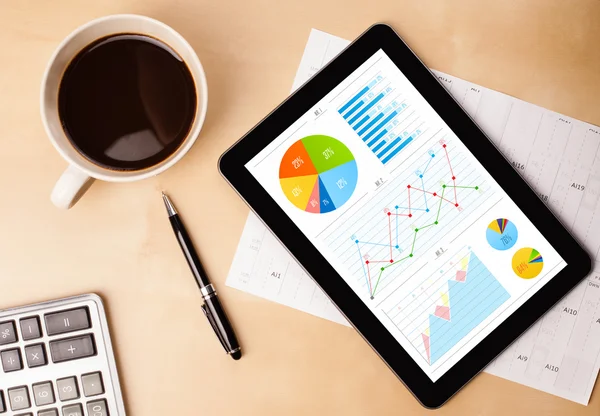 Tablet-PC zeigt Diagramme auf dem Bildschirm mit einer Tasse Kaffee auf dem Schreibtisch — Stockfoto