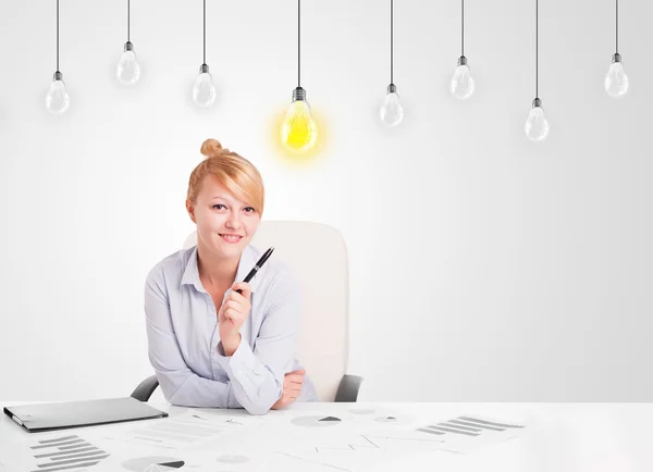 Zakelijke vrouw zit aan tafel met idee gloeilampen — Stockfoto