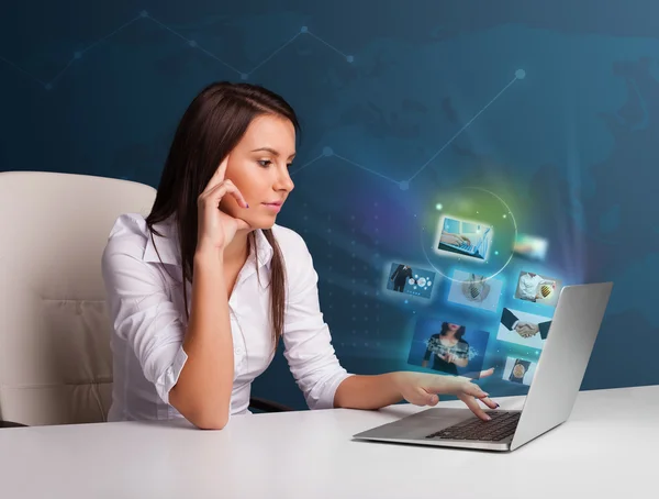 Beautiful girl sitting at desk and watching her photo gallery on — Stock Photo, Image