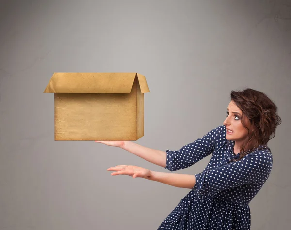 Mujer joven sosteniendo una caja de cartón vacía — Foto de Stock