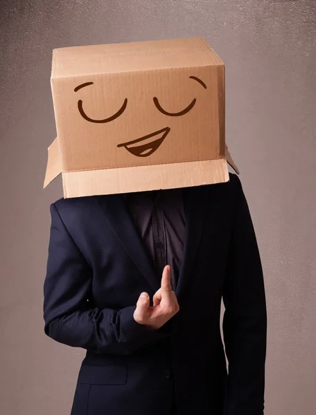 Young man gesturing with a cardboard box on his head with smiley — Stock Photo, Image