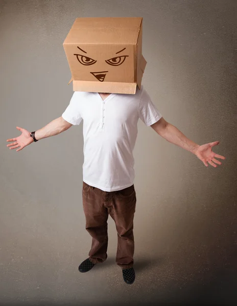 Young man gesturing with a cardboard box on his head with evil f — Stock Photo, Image