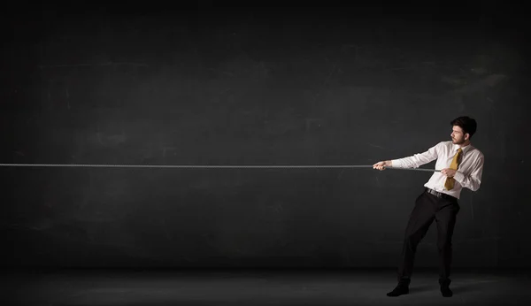 Businessman pulling rope on grey background — Stock Photo, Image