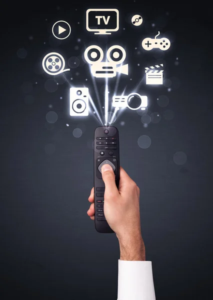 Hand with remote control and media icons — Stock Photo, Image