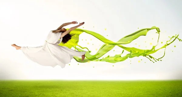 Красивая девушка прыгает с зеленым абстрактным жидким платьем — стоковое фото