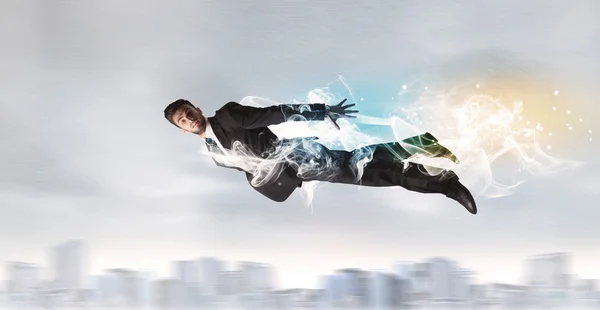 Hero superman flying above city with smoke left behind — Stock Photo, Image
