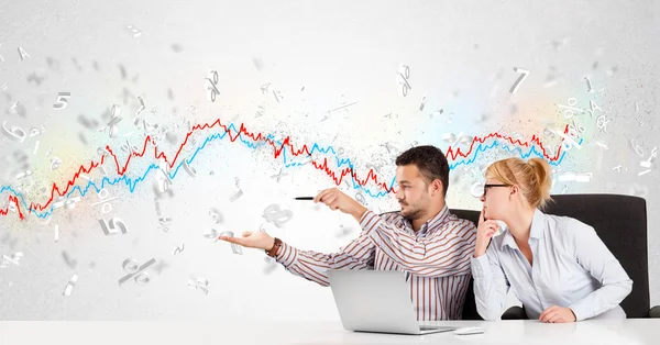 Business man and woman sitting at table with stock market graph — Stock Photo, Image