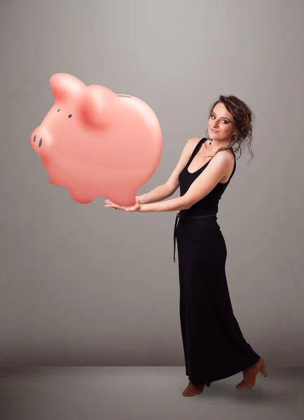 Junges Mädchen hält ein riesiges Sparschwein — Stockfoto