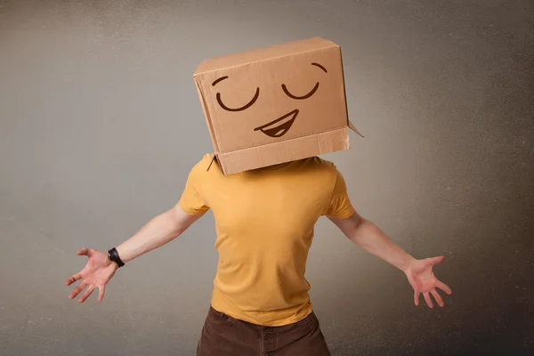 Jeune homme gesticulant avec une boîte en carton sur la tête avec un sourire — Photo