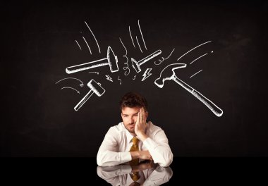 Depresyondaki işadamı çekiç izlerinin altında oturuyor