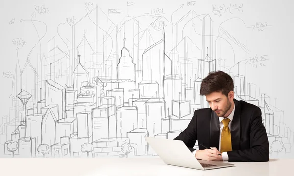 Businessman sitting at the white table with hand drawn buildings — Stock Photo, Image