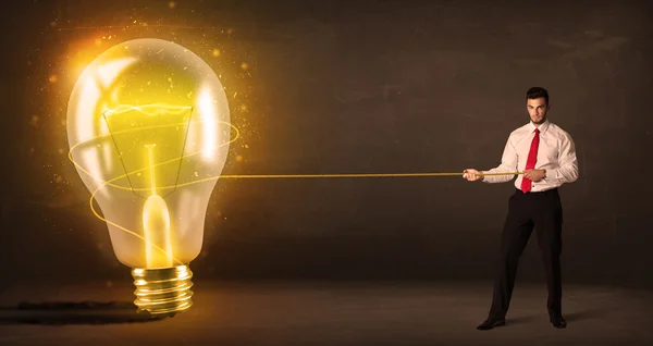 Hombre de negocios tirando de una gran bombilla brillante brillante — Foto de Stock