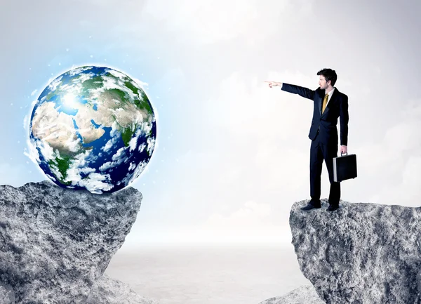 Businessman on rock mountain with a globe — Stock Photo, Image
