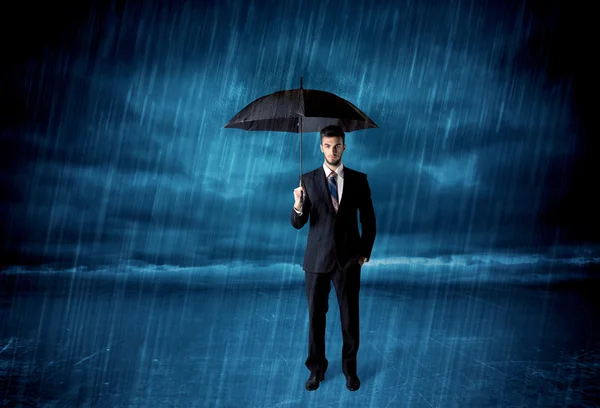 Hombre de negocios de pie bajo la lluvia con un paraguas —  Fotos de Stock