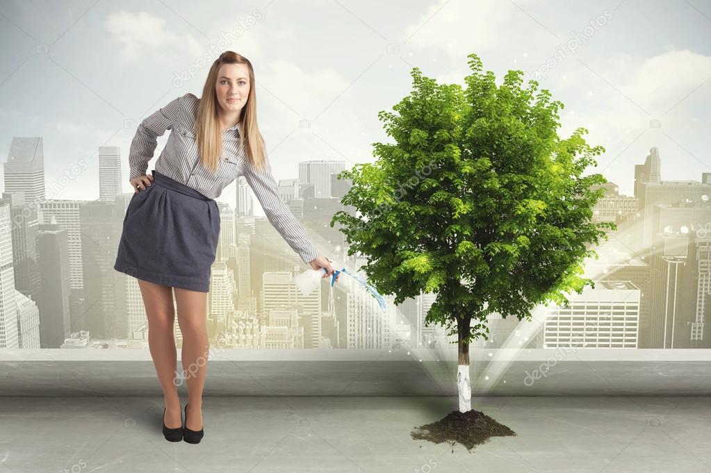 Businesswoman watering green tree on city background