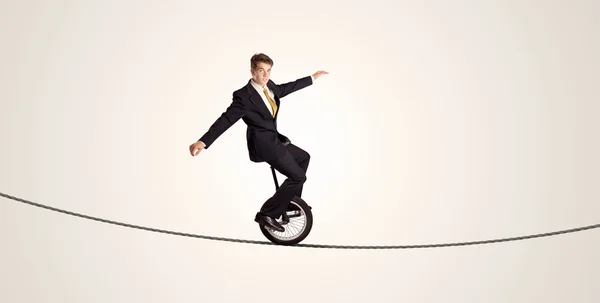 Uomo d'affari estremo cavalcando monociclo su una corda — Foto Stock