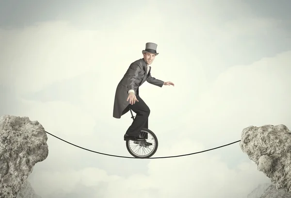 Храбрый бизнесмен ездит на моноцикле между скалами — стоковое фото