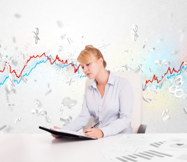 Borsa grafiğiyle masada oturan iş kadını. 