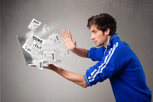 Young man holding a laptop and reading the explosive news — Stock Photo, Image