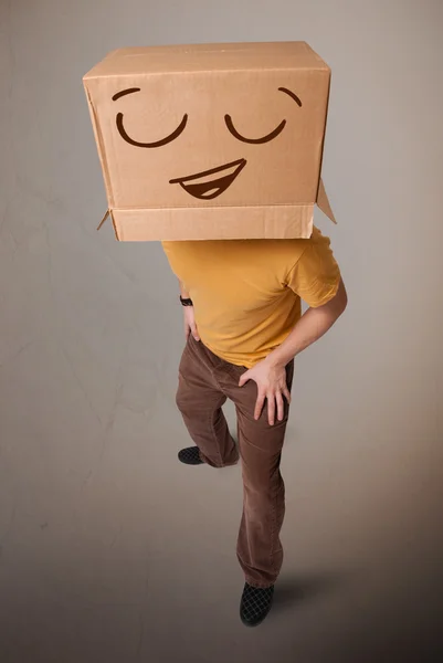 웃는 그의 머리에 마분지 상자와 함께 몸짓 하는 젊은 남자 — 스톡 사진