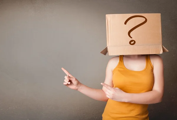 Jeune femme gestuelle avec une boîte en carton sur la tête avec quête — Photo