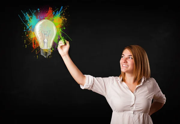 Jeune femme dessinant une ampoule colorée avec éclaboussures colorées — Photo