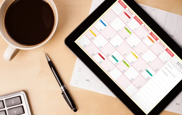 Tablet pc mostrando calendário na tela com uma xícara de café em um d — Fotografia de Stock