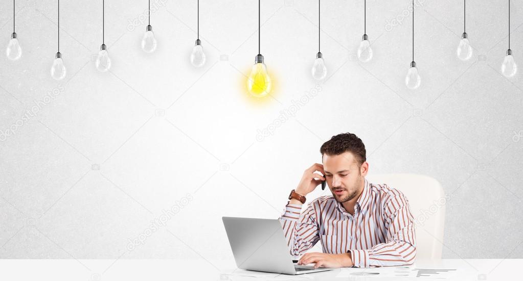 Business man sitting at table with idea light bulbs