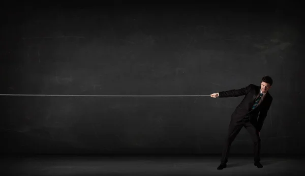 Businessman pulling rope on grey background — Stock Photo, Image