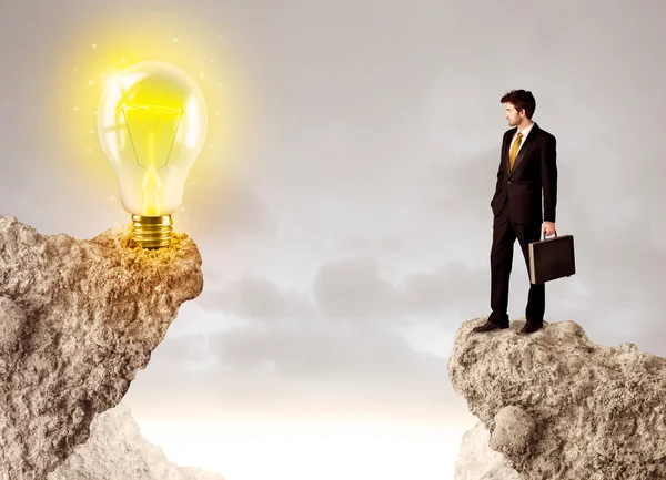 Businessman on rock mountain with idea bulb — Stock Photo, Image