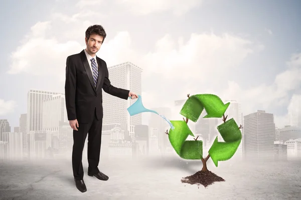 Biznes człowiek podlewanie zielony recycle znak drzewo na tle miasta — Zdjęcie stockowe
