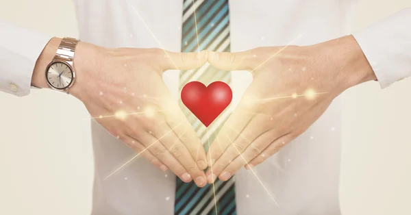 Manos creando una forma con un corazón brillante — Foto de Stock