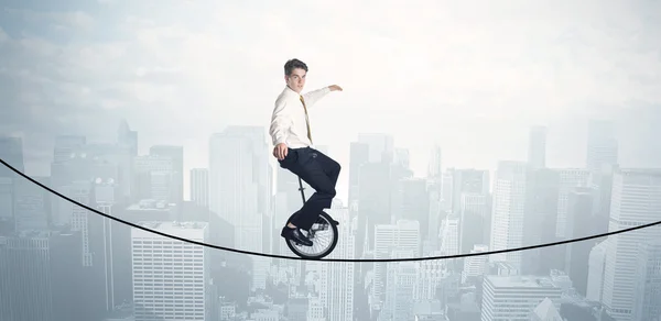 Homem corajoso montando um monociclo em uma corda acima da paisagem urbana — Fotografia de Stock