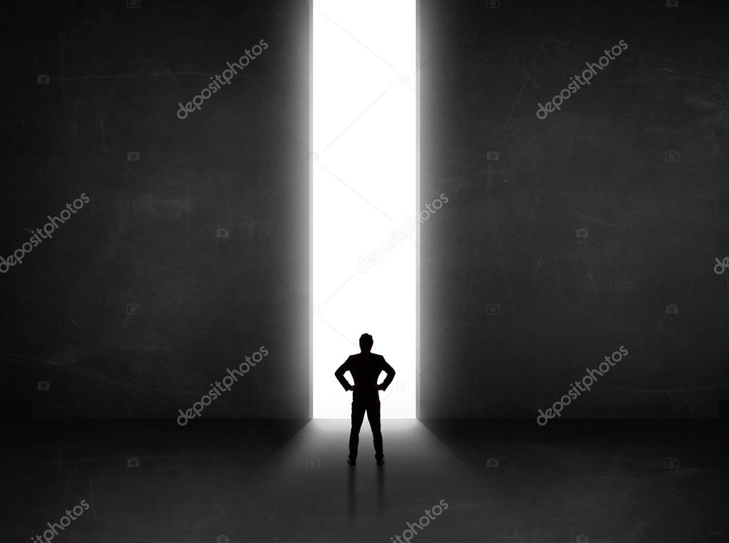 Business person looking at wall with light tunnel opening 