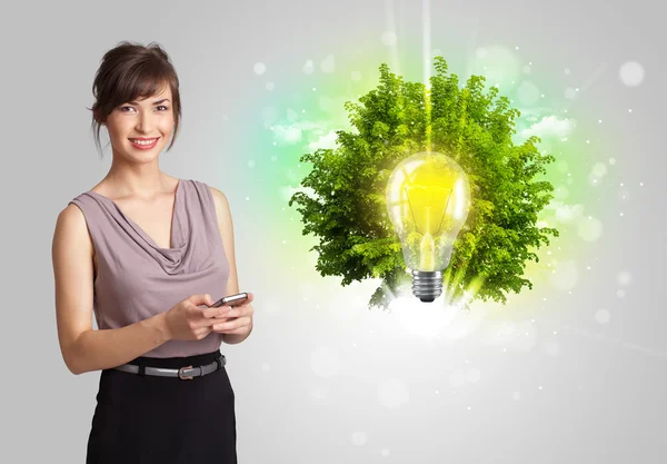 Giovane ragazza che presenta idea lampadina con albero verde — Foto Stock