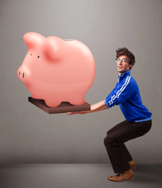 Bonito homem segurando um enorme banco de poupança porquinho — Fotografia de Stock