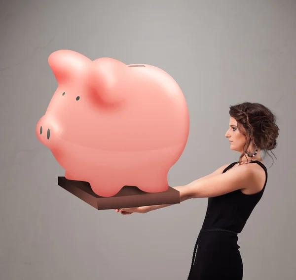 Jovem segurando uma enorme poupança porquinho banco — Fotografia de Stock