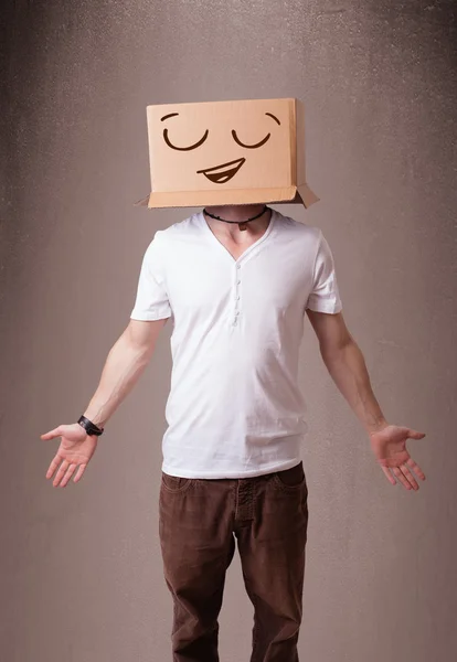 Jeune homme gesticulant avec une boîte en carton sur la tête avec un sourire — Photo