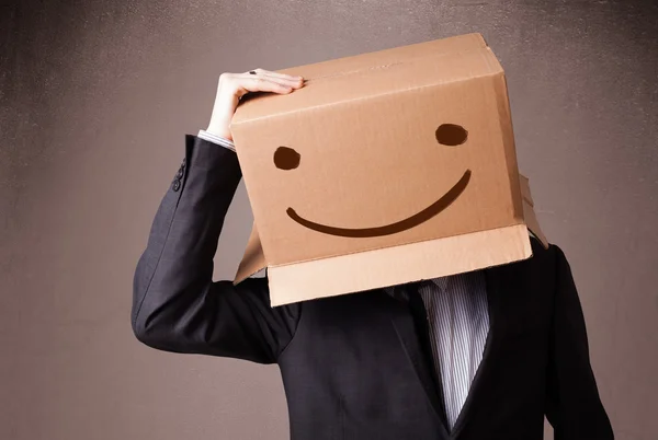 Businessman gesturing with a cardboard box on his head with smil — Stock Photo, Image