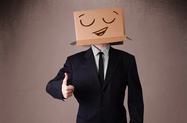 Empresário gesticulando com uma caixa de papelão na cabeça com smil — Fotografia de Stock