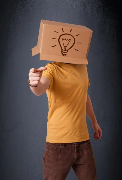 Joven haciendo gestos con una caja de cartón en la cabeza con luz — Foto de Stock