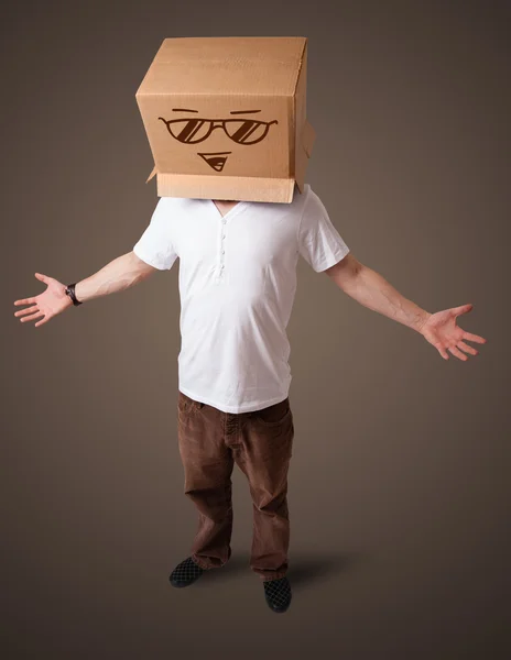 Young man gesturing with a cardboard box on his head with smiley — Stock Photo, Image