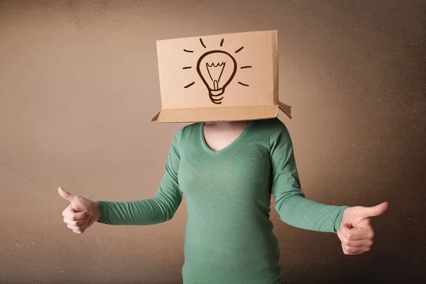 Young woman gesturing with a cardboard box on her head with ligh — Stock Photo, Image