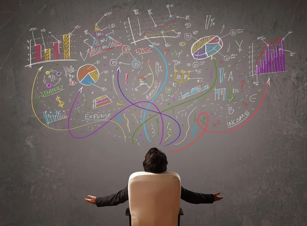 Young business man looking at sketches of graphs and symbols — Stock Photo, Image